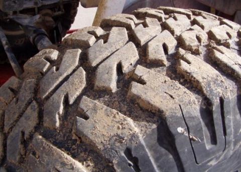 1991 Ford Bronco - The aggressive tread pattern of this tire is caked with mud, suggesting recent off-road use.