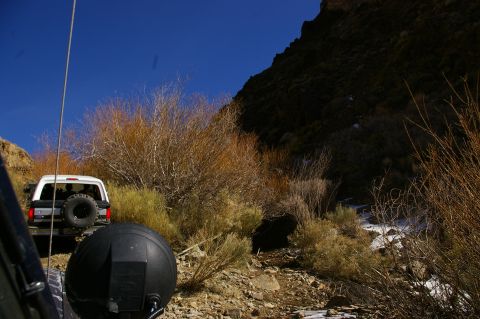1986 Ford Bronco - Two vehicles on a dirt road in a mountainous, arid landscape.