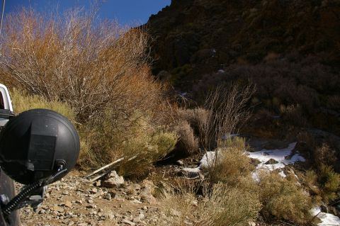 1986 Ford Bronco - A vehicle's auxiliary light is visible in a dry, brush-filled landscape with patches of snow.