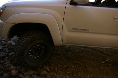 1986 Ford Bronco - White Toyota Tacoma truck side view on a rocky surface.