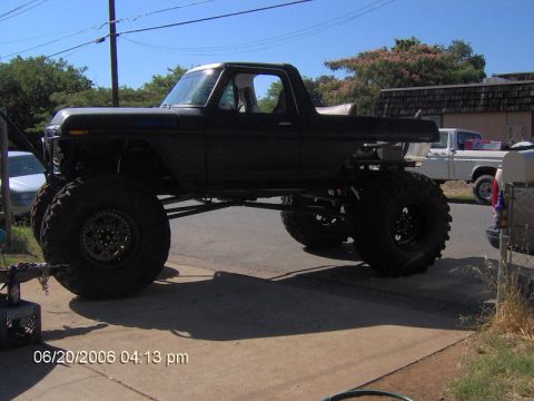 1991 Ford Bronco - This heavily modified 1978 Ford Bronco features an extreme lift kit and oversized tires, parked on a sunny day.