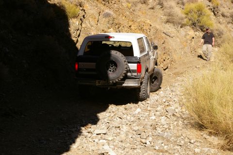 1986 Ford Bronco - Ford Bronco navigates a challenging, off-road trail in a desert-like environment.