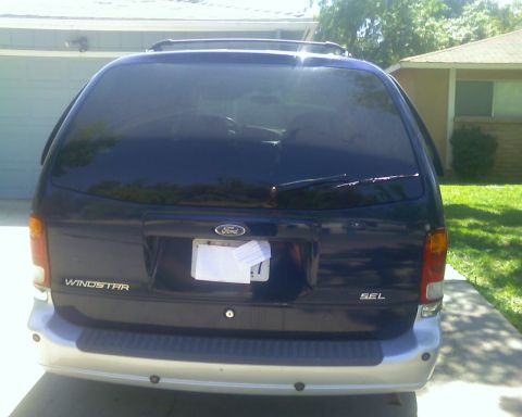 2000 Ford Windstar - The rear of a dark blue Ford Windstar van is shown, with a license plate and 'SEL' trim visible.