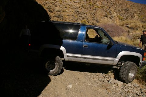 1986 Ford Bronco - A blue SUV with silver trim is parked on a rocky path, with a person visible in the background.