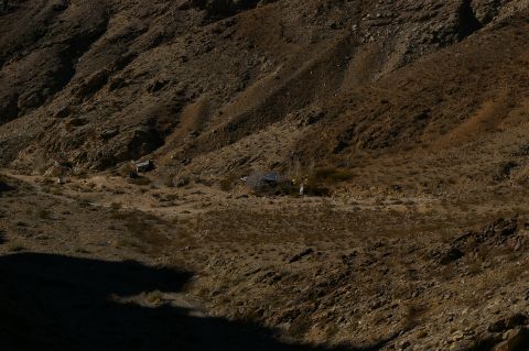 1986 Ford Bronco - A wide shot of a remote desert area with some structures and vehicles visible.
