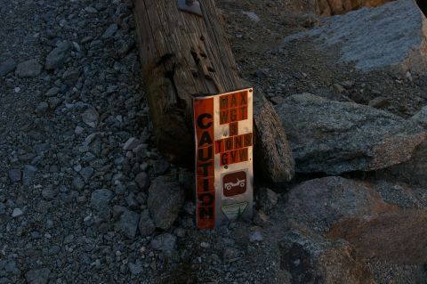1986 Ford Bronco - A weathered sign with weight restrictions is attached to a wooden post amidst rocks and gravel.