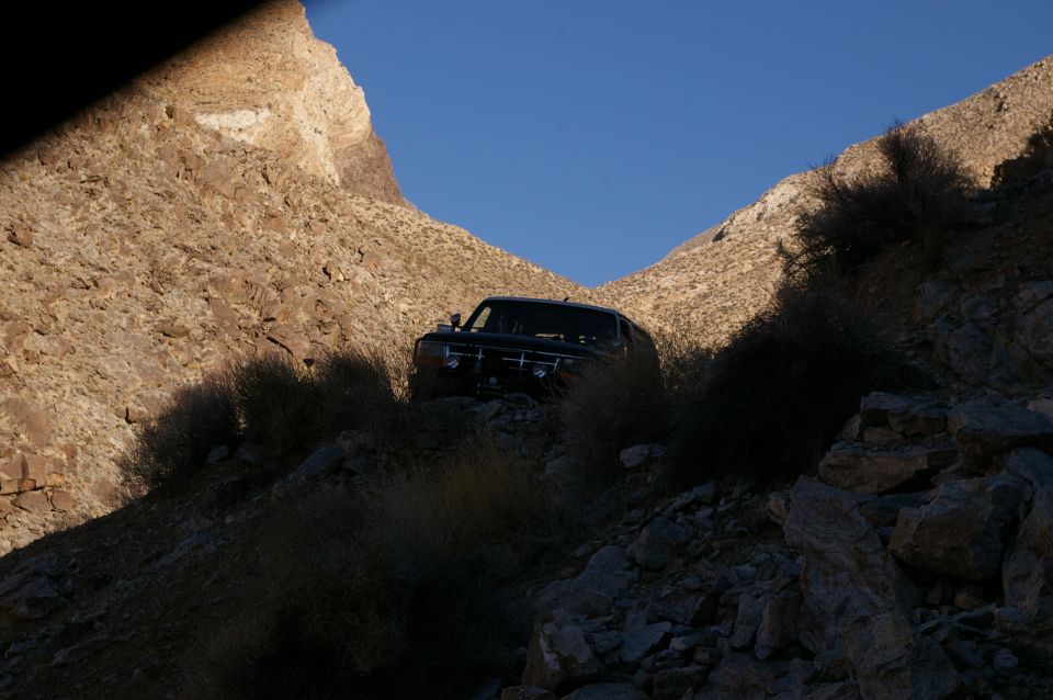 Black SUV on a rocky, desert slope with sparse brush