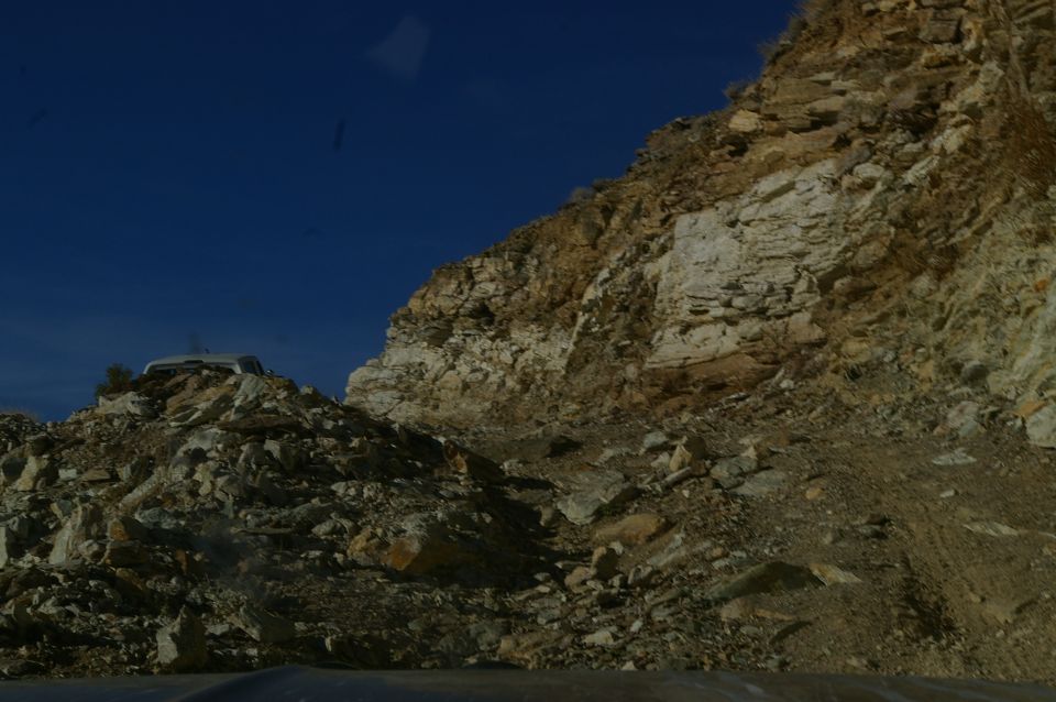 White SUV parked on a rocky incline under a clear blue sky