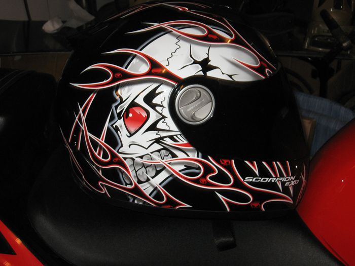 Motorcycle helmet with a skull graphic and flames. Text reads 'SCORPION EXO'
