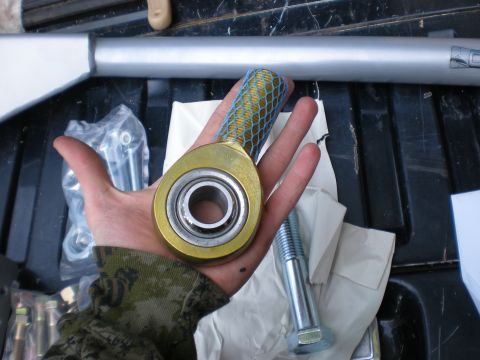 1993 Ford Bronco - A hand holds a rod end joint, with other vehicle parts visible in the background.