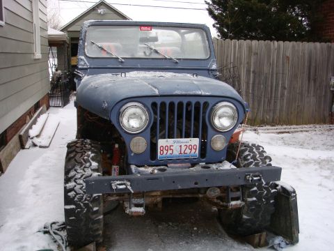 1980 Jeep CJ5 - A blue Jeep CJ sits in a snowy yard, its front grille and headlights visible.
