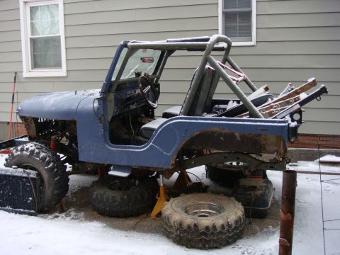 1980 Jeep CJ5 - A blue Jeep CJ5 body, partially disassembled and on jack stands, sits outside in the snow.
