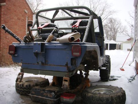 1980 Jeep CJ5 - A blue Jeep CJ5 is parked on jack stands in the snow, showing its rear end and roll cage.