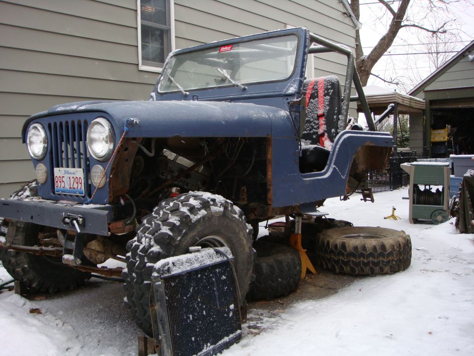 Blue 1980 Jeep CJ5 with large tires, jacked up in snow