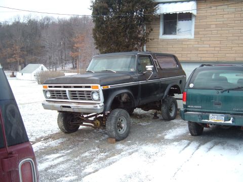 1979 Ford Bronco - A black Ford Bronco with a lifted suspension sits in a snowy driveway next to another vehicle.
