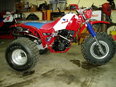 2000 Ford E350 - A red and white three-wheeled ATV is parked indoors, showing its large tires and suspension system.