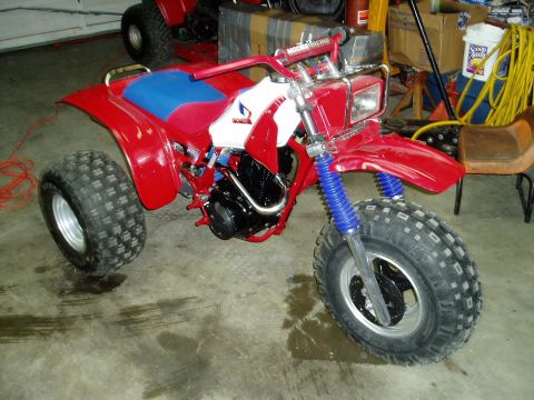 2000 Ford E350 - A red three-wheeled ATV sits in a garage next to another ATV.