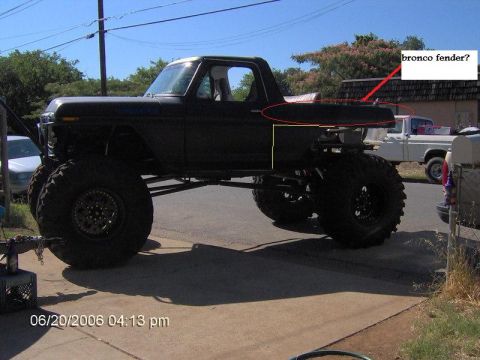 1991 Ford Bronco - A heavily modified black pickup truck is shown with oversized tires and lifted suspension. Another white pickup truck is visible in the bac…