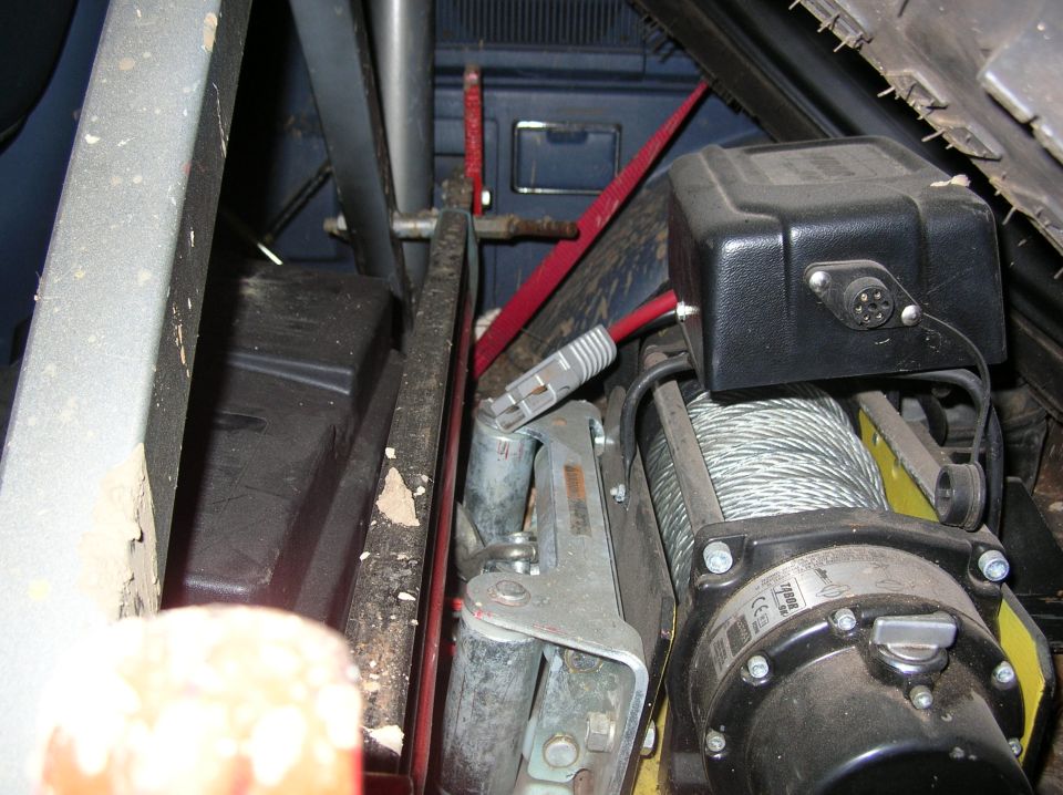 Warn Tabor-9K winch in cradle, locked down w/key. High-lift jack mounted to rollbar X-brace, positioned behind front seats and under spare tire.
