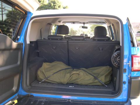 2007 Toyota FJ Cruiser - The rear cargo area of a blue 2007 Toyota FJ Cruiser is shown with a large green bag and a speaker.