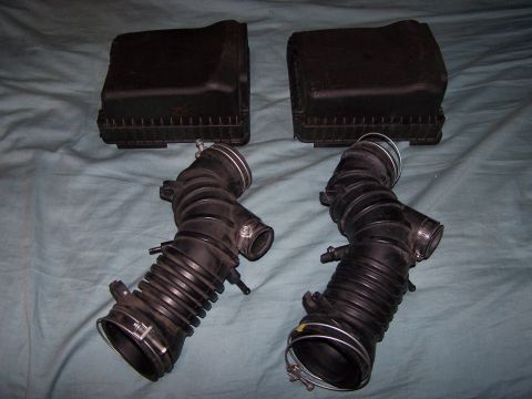 1995 Ford Probe - Two black air intake hoses and air filter boxes are displayed on a blue cloth surface.
