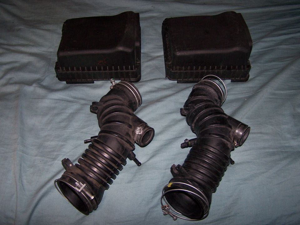 Two black air intake hoses and air filter boxes on a blue cloth background