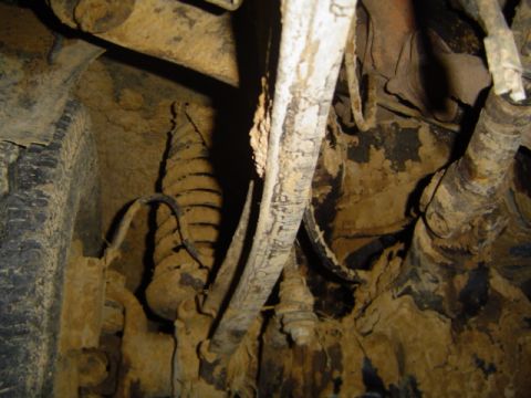 1979 Ford Bronco - Undercarriage view showing significant rust and mud accumulation on various vehicle parts.