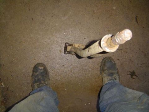 1979 Ford Bronco - A rusty metal component with a threaded end is shown on a concrete floor, with two pairs of feet visible.