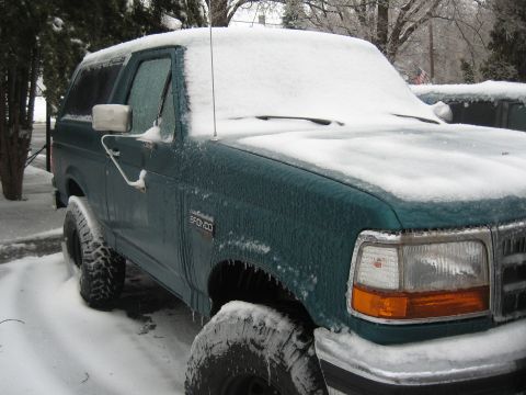 1996 Ford Bronco - Teal Ford Bronco covered in ice and snow, parked outdoors in winter.