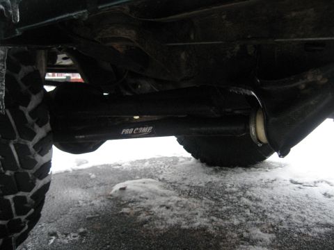 1996 Ford Bronco - A close-up view of the undercarriage shows a PRO COMP suspension component and a tire, with snow on the ground.