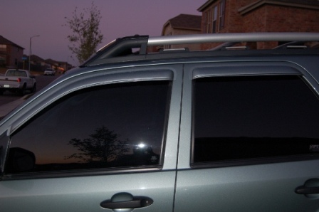 2006 Ford Escape - A gray SUV with tinted windows and a roof rack is parked on a residential street during twilight.