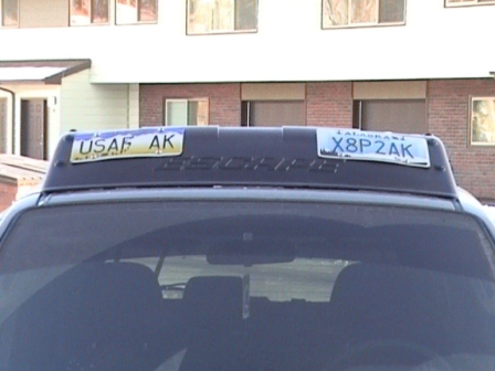 2006 Ford Escape - Two Alaskan license plates are attached to the roof rack of a dark SUV.