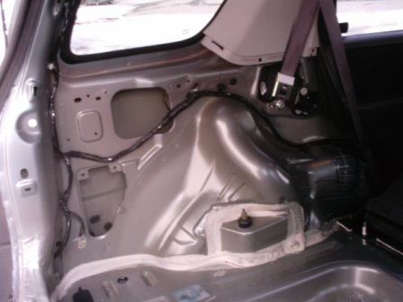 2006 Ford Escape - The interior of a vehicle's rear wheel well shows exposed metal and wiring, suggesting a part or installation detail.