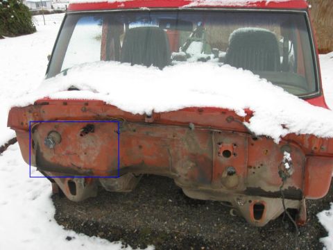 1979 Ford Bronco - The exposed firewall of a red vehicle, partially covered in snow, reveals its internal structure and mounting points.