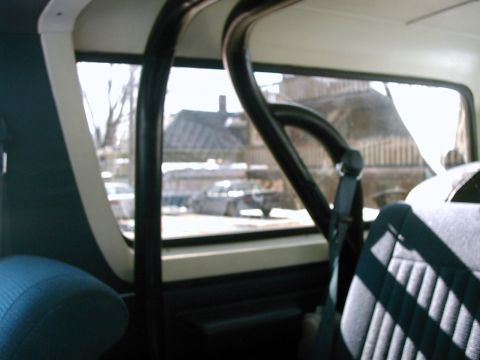 1987 Ford Bronco - View from inside a vehicle, looking out through the windows at buildings and another car.