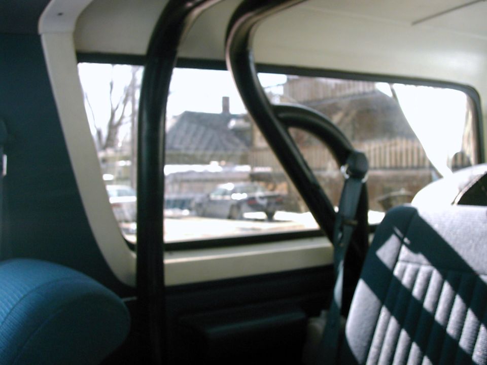Interior view of a vehicle, showing a roll cage and seats. A watermark reads SUPERMOTORS
