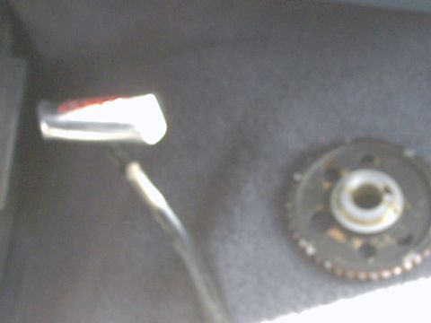 1987 Ford Bronco - A close-up view of a mechanical component, possibly from an engine, with a toothed wheel and a reflective surface.