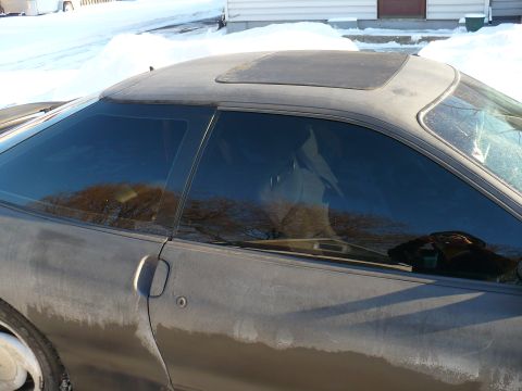 1993 Ford Probe - A gray car with tinted windows and a sunroof is parked outside in a snowy environment.