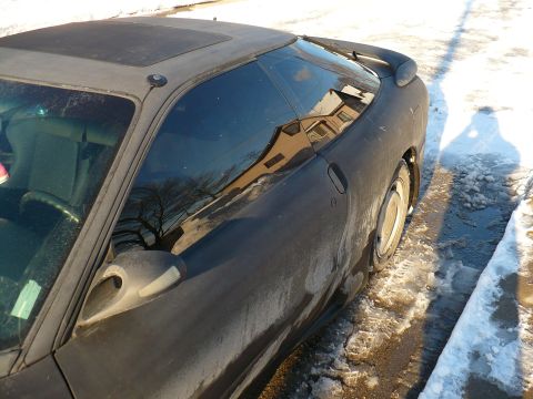1993 Ford Probe - Side profile of a dark 1993 Ford Probe coupe with tinted windows and a rear spoiler, parked on a snowy road.