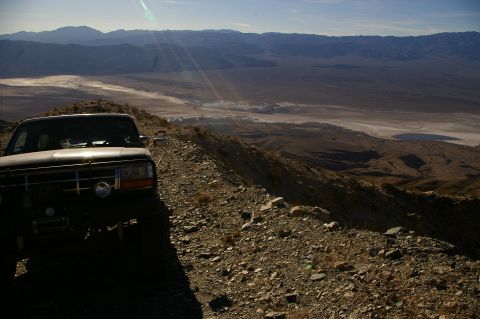 1986 Ford Bronco - A Ford Bronco is parked on a mountain ridge with a vast desert landscape in the background.