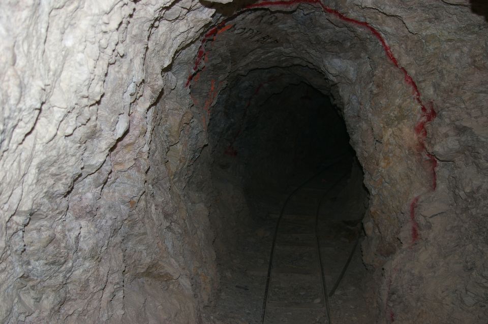 dark mine tunnel with tracks on the floor and red markings on the wall