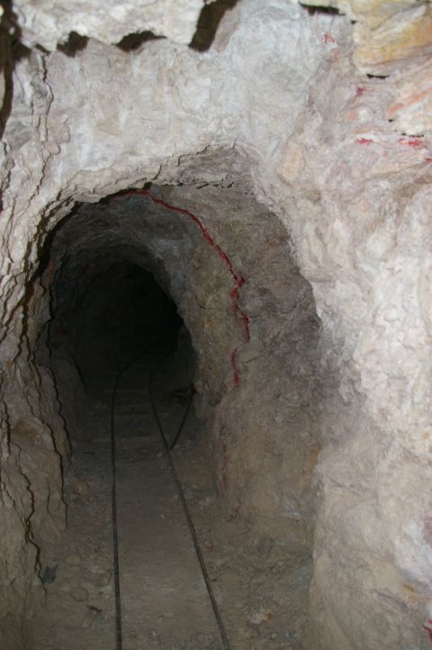 1986 Ford Bronco - Interior view of a mine tunnel showing tracks and rough-hewn walls with red markings.