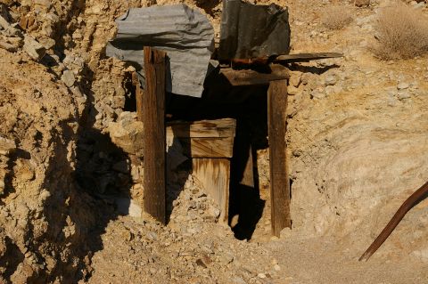 1986 Ford Bronco - A weathered wooden structure marks the entrance to a mine, surrounded by dry, rocky earth and debris.