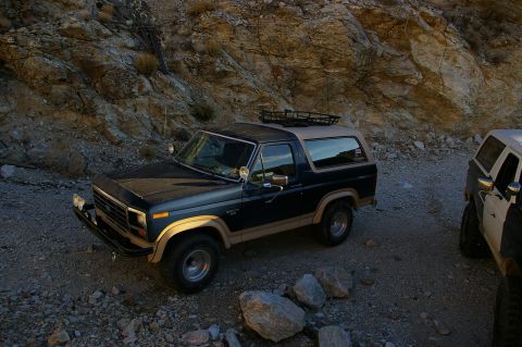 1986 Ford Bronco - A 1986 Ford Bronco parked on a rocky trail next to another Bronco.