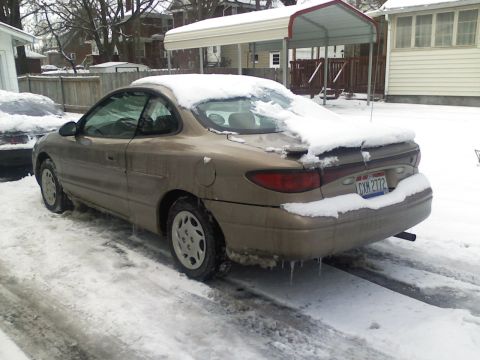2004 Yamaha FZR600 - A gold Ford Escort coupe sits covered in snow, with icicles hanging from its rear bumper.
