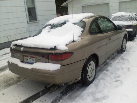 2004 Yamaha FZR600 - A tan coupe sits covered in snow, parked next to another vehicle in a snowy driveway.