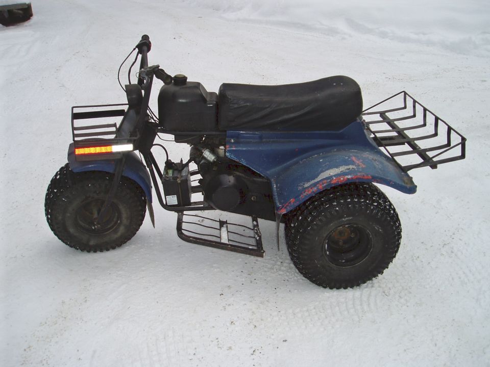 Weathered blue three-wheeler ATC with cargo racks parked on packed snow