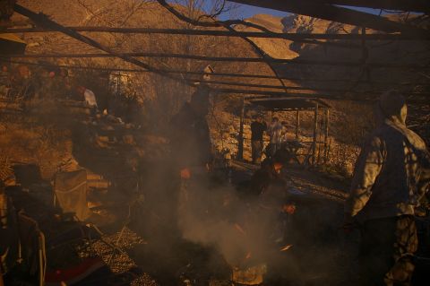 1986 Ford Bronco - A group of people are gathered around a fire under a rustic shelter, with smoke obscuring the scene.