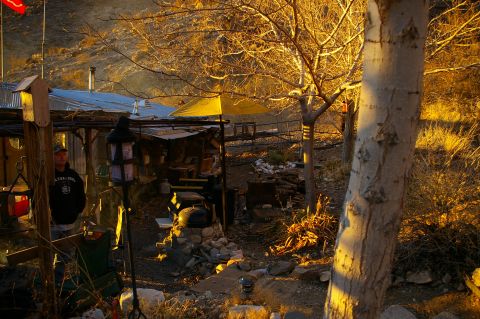 1986 Ford Bronco - A rural scene unfolds with a person standing near a rustic structure, bathed in the warm glow of late afternoon sun.