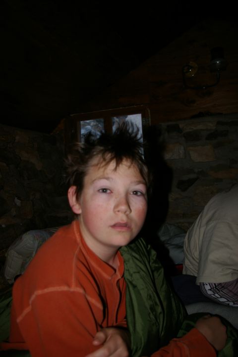 1986 Ford Bronco - A young boy sits in a sleeping bag inside a rustic room with stone walls and a wooden ceiling.